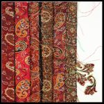 Gallery 2 - handmade fabric jewelry laid on the right side of multiple folded fabircs