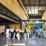 Gallery 5 - Kids and adults interacting with 20' immersive stellated icosahedron form clad in colored acrylic.