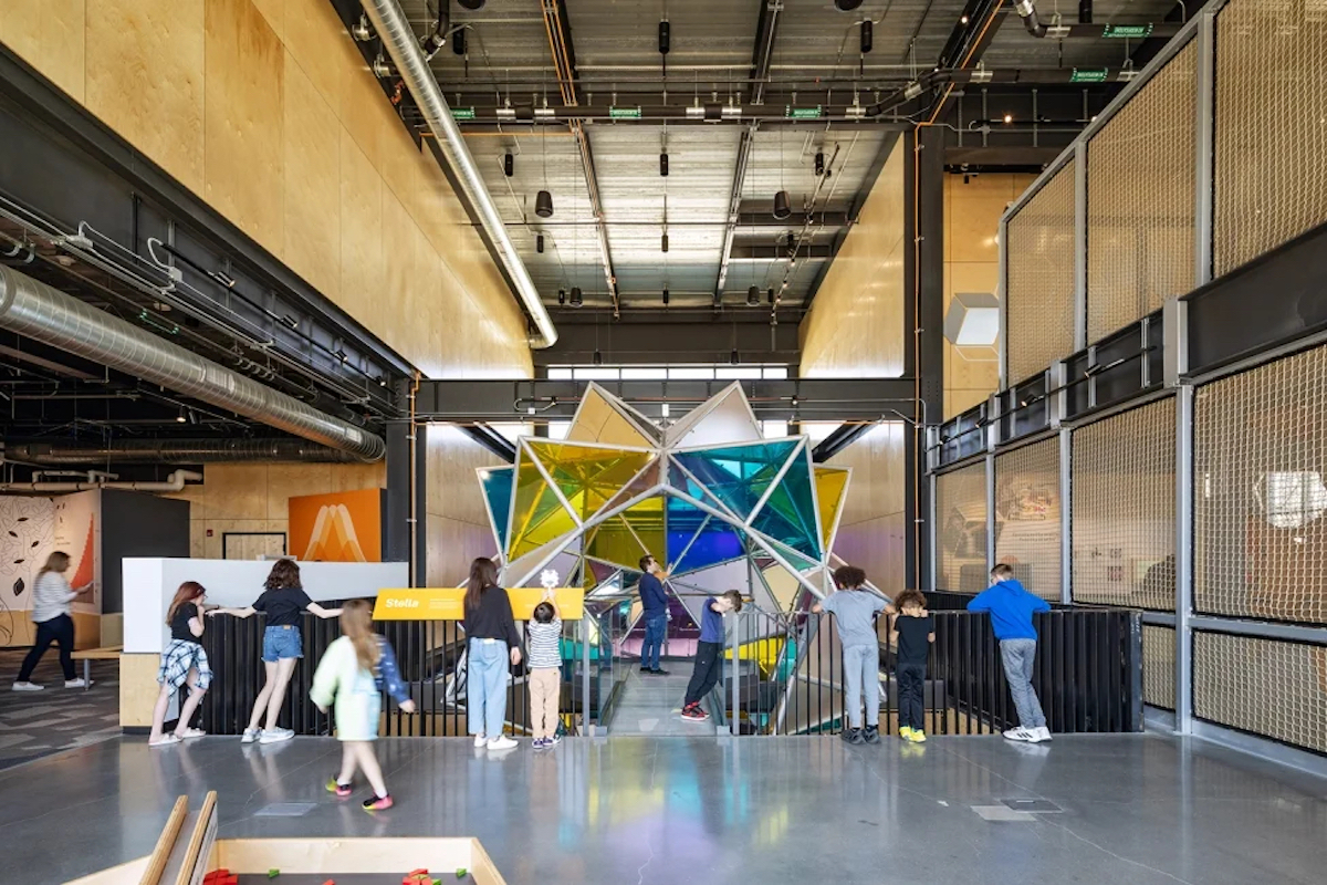 Gallery 5 - Kids and adults interacting with 20' immersive stellated icosahedron form clad in colored acrylic.