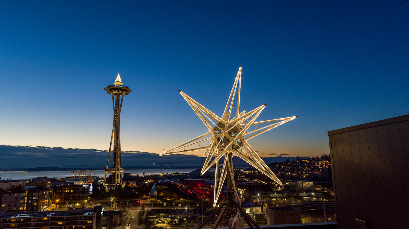 Gallery 6 - 20' 12-pointed illuminated star sculpture pictured against Seattle skyline at dusk.