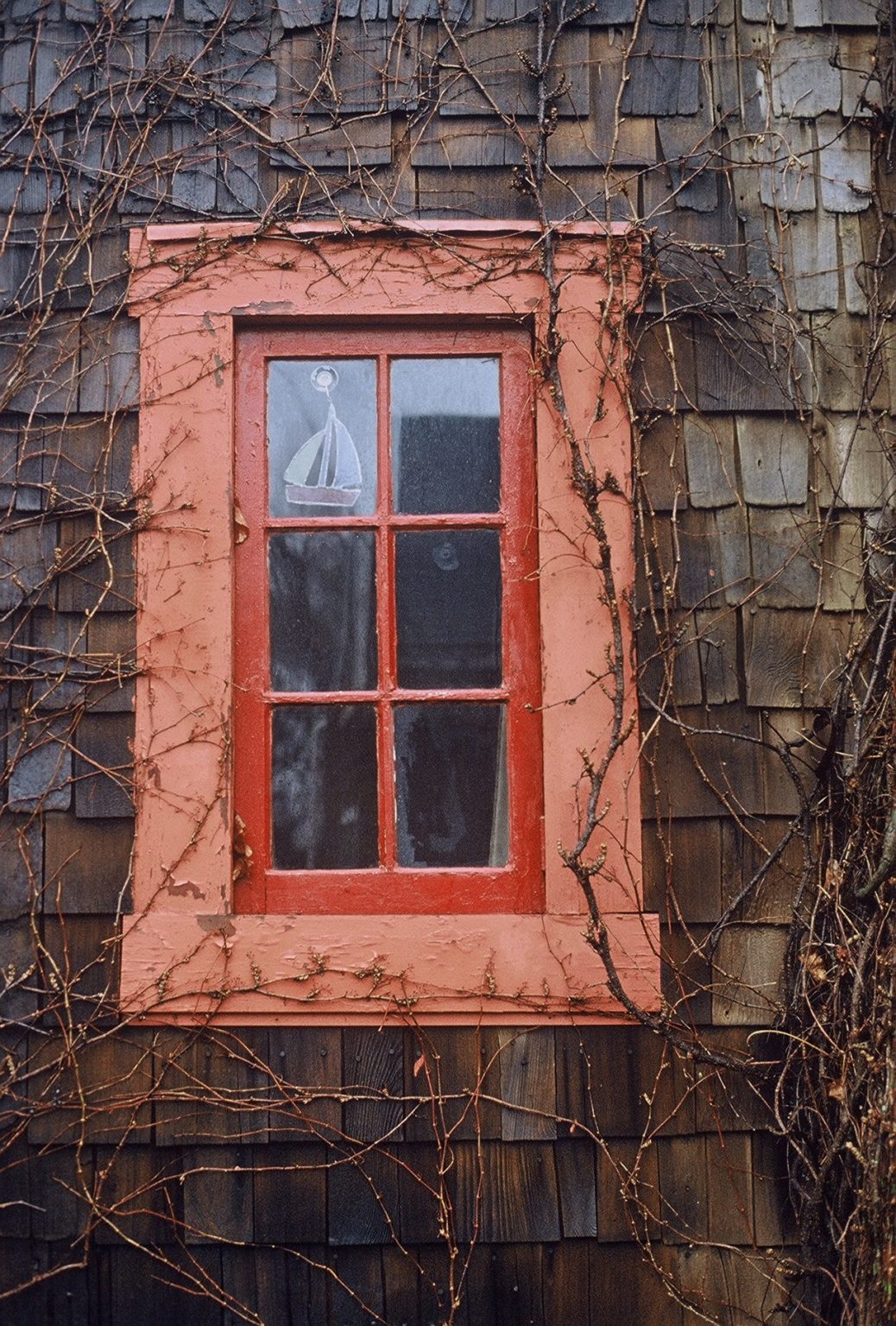Gallery 1 - image of an orange window frame with 6 small glasses and a sticker of a sailboat at the top left corner.