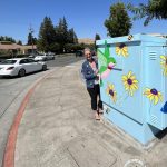 Gallery 1 - Picture of the artist to the left of the Utility Box Art on a sunny day