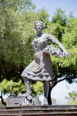 The Cannery Lady, A life size bronze statue of a woman, holding a tray of asparagus and tomatoes and empty cans at her feet.