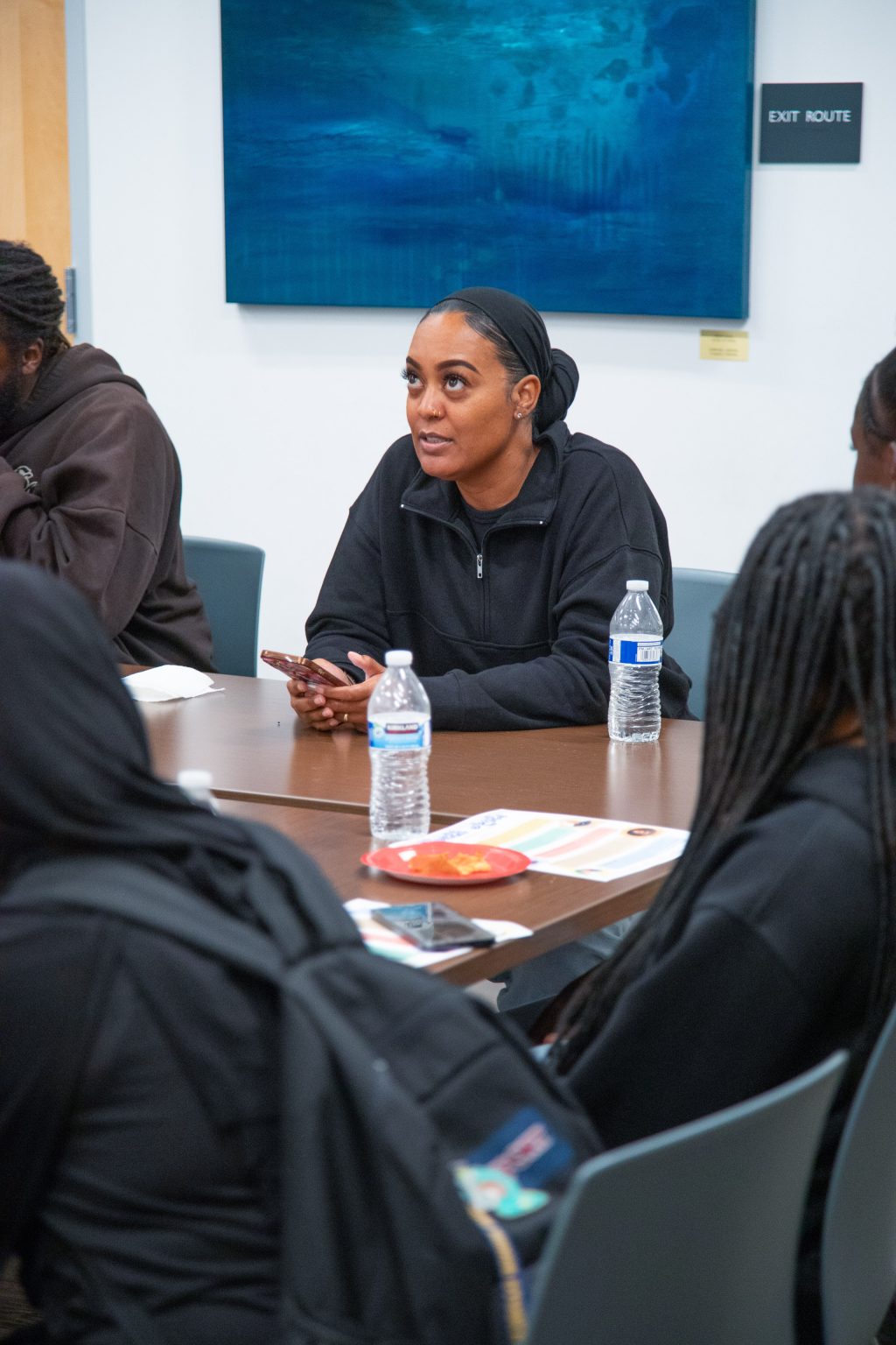 Gallery 5 - Monique McCoy sitting at a table, sharing an original poem at a Youth Arts Connection workshop at the Antioch Library.