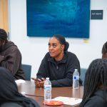 Gallery 5 - Monique McCoy sitting at a table, sharing an original poem at a Youth Arts Connection workshop at the Antioch Library.