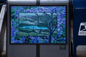 A utility box features a landscape painting of the San Pablo Reservoir viewed through the branches of a dark, twisting tree. The central image is framed by a dense border of vibrant purple hydrangeas, and a small plaque encourages viewers to find six hidden animals.