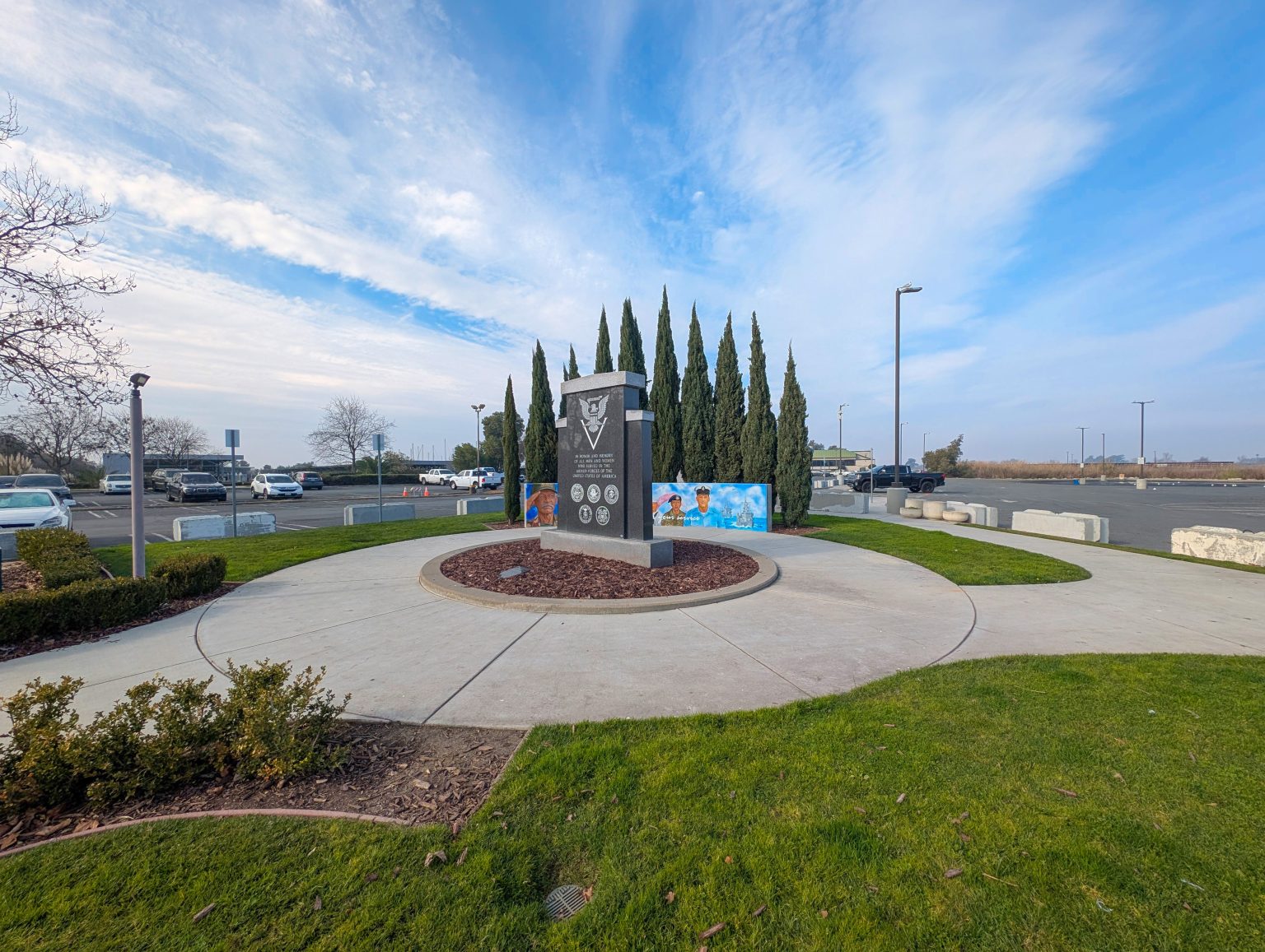 Gallery 3 - A wide outdoor mural on a low concrete wall depicting six military service members in various uniforms, including a veteran in a saluting pose. The center includes the message 