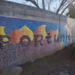 Gallery 5 - A colorful mosaic mural on a curved concrete wall displays the word 