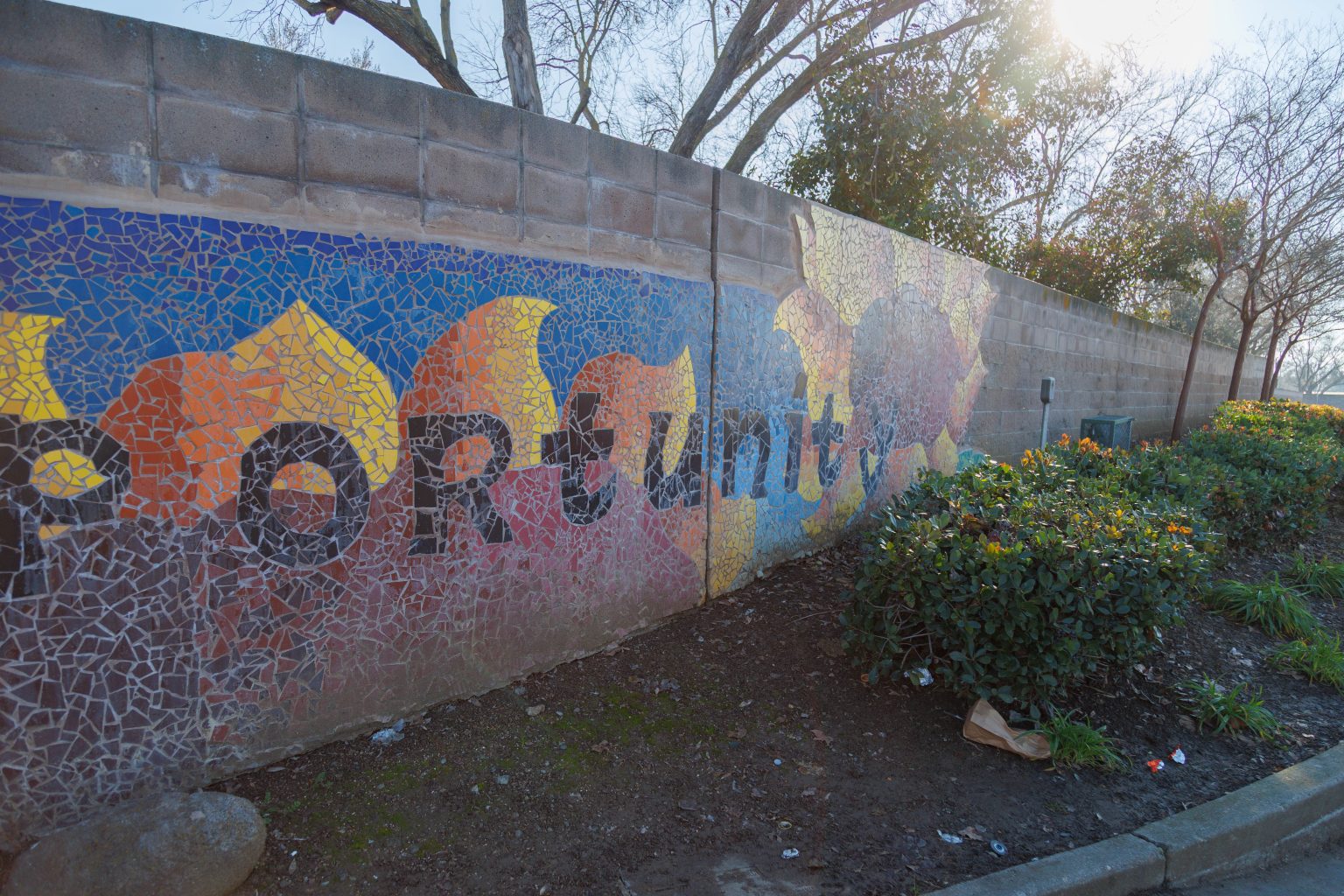 Gallery 5 - A colorful mosaic mural on a curved concrete wall displays the word 