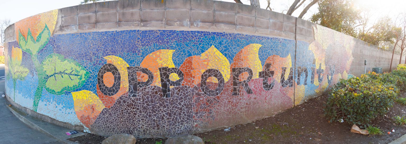 Gallery 4 - A colorful mosaic mural on a curved concrete wall displays the word 