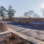 Gallery 3 - A colorful mosaic mural on a curved concrete wall displays the word 