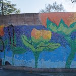 Gallery 2 - A colorful mosaic mural on a curved concrete wall displays the word 