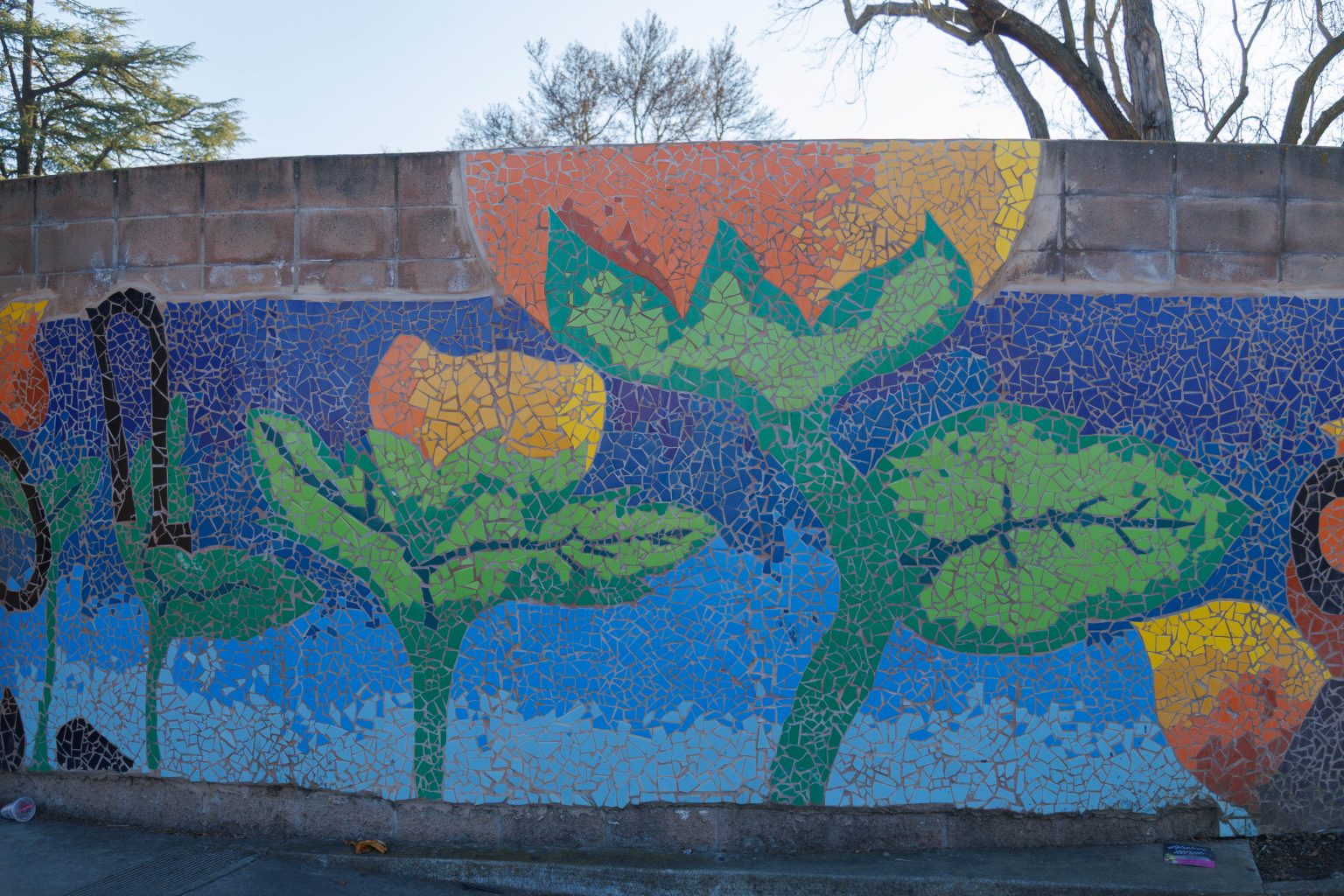Gallery 2 - A colorful mosaic mural on a curved concrete wall displays the word 