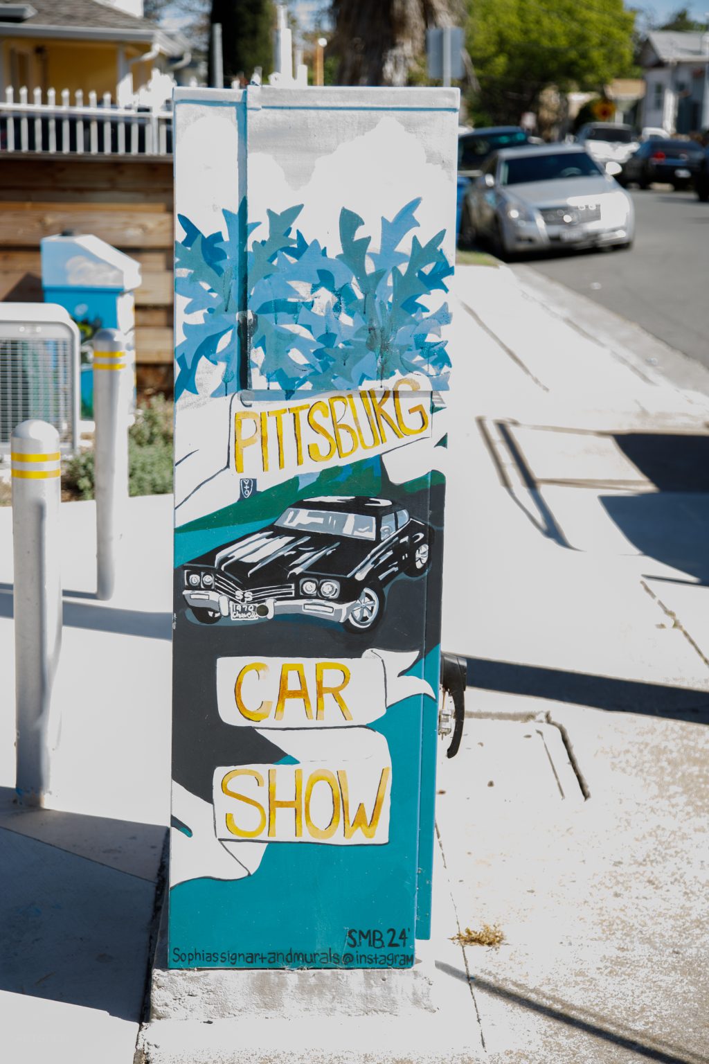 Gallery 2 - A series of three utility boxes painted with colorful murals. One box shows a classic black car with 