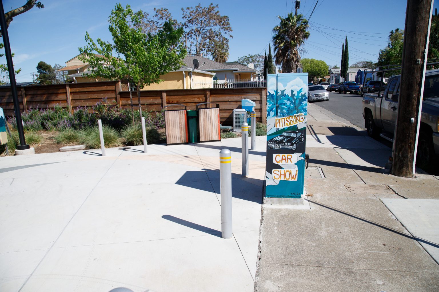 Gallery 3 - A series of three utility boxes painted with colorful murals. One box shows a classic black car with 