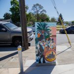 Gallery 5 - A series of three utility boxes painted with colorful murals. One box shows a classic black car with 