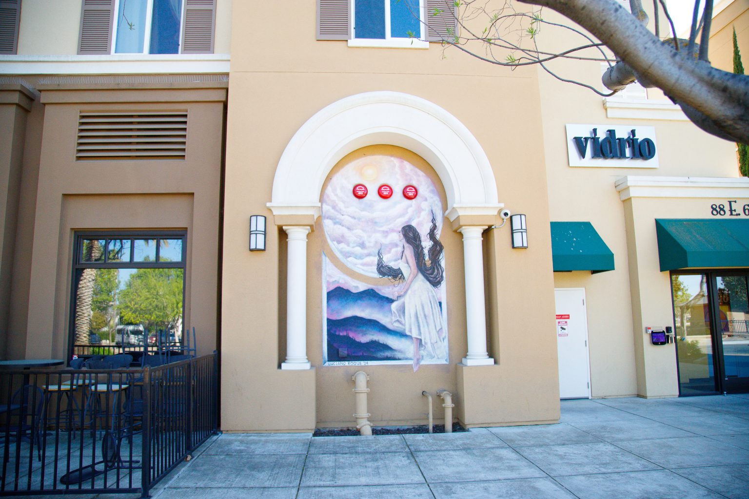 Gallery 2 - A large-scale mural on the side of a commercial building featuring bold, colorful portraiture blended with geometric shapes and flora. The composition uses a warm palette of oranges and teals to highlight the intersection of the city's industrial heritage and its community growth.