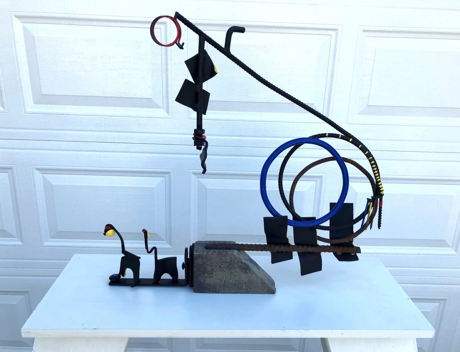 Gallery 7 - Forged and bent steel; plate, rod, bolts, radiator clamp, screws.  Rusted and painted. Stone base. 