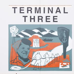 A mural featuring graphic shapes, including a large portrait of a woman wearing a hair bandana, figures pulling a rope, mountains, and ships under the text "TERMINAL THREE".