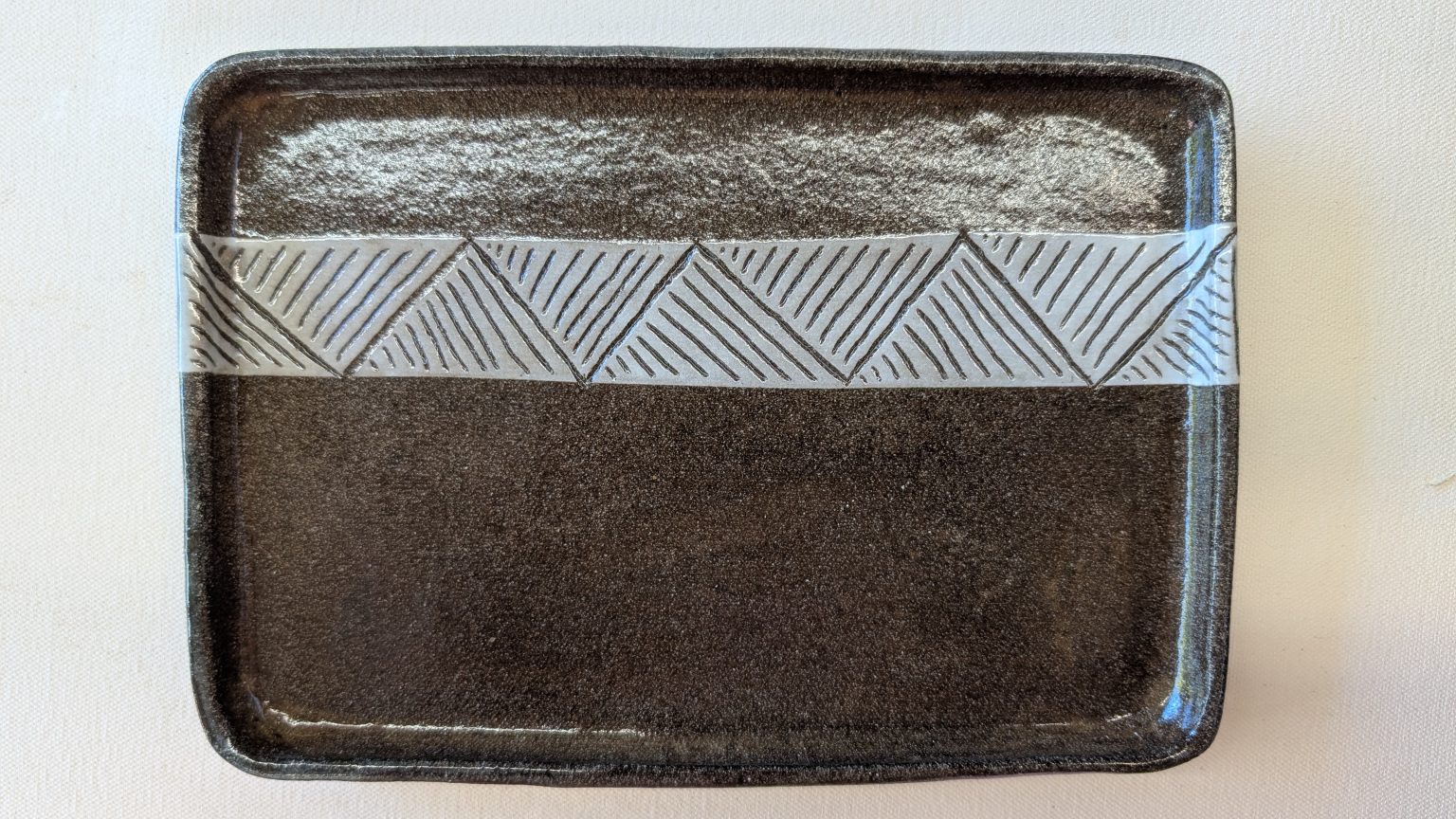 Gallery 2 - Rectangular platter made from dark clay, with a white carved stripe across the top