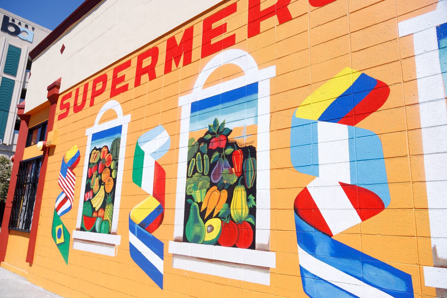 Gallery 1 - Alt Text: A painted mural on an orange cinder block wall displays the word 