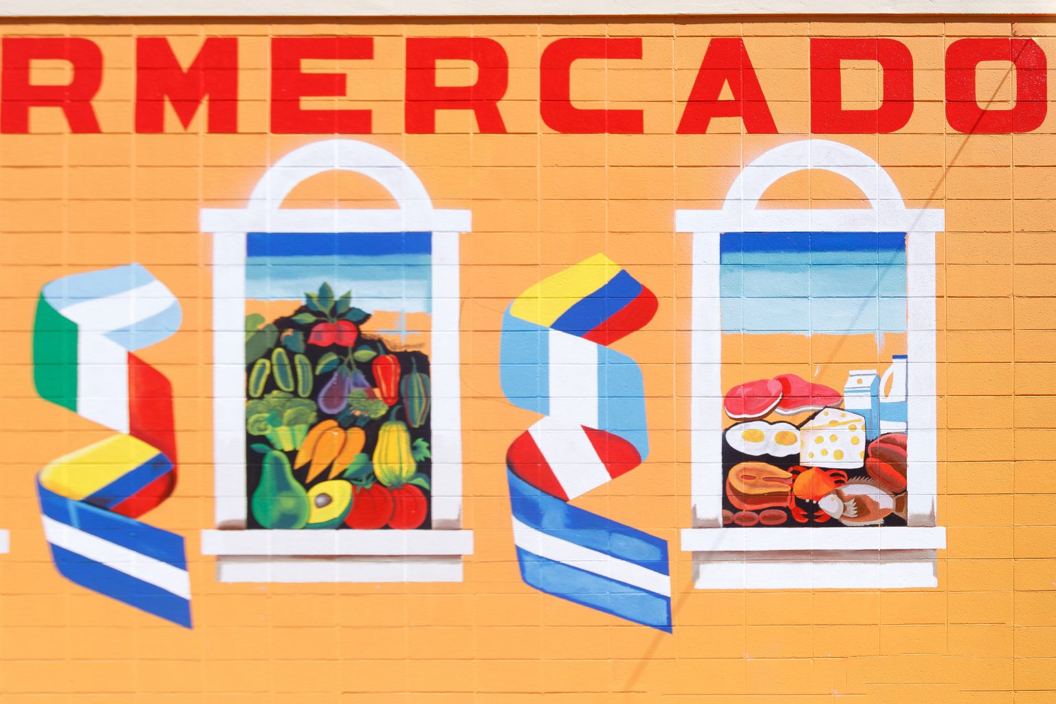 Gallery 2 - Alt Text: A painted mural on an orange cinder block wall displays the word 
